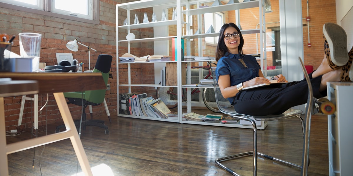 women in the office with her feet kicked up, smiling