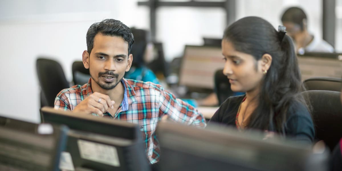 two coworkers collaborating in an office with a computer in front of them