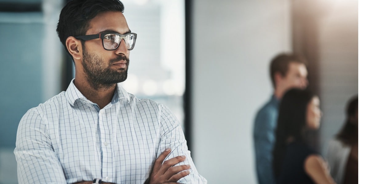 businessman with glasses and his arms crossed looking away