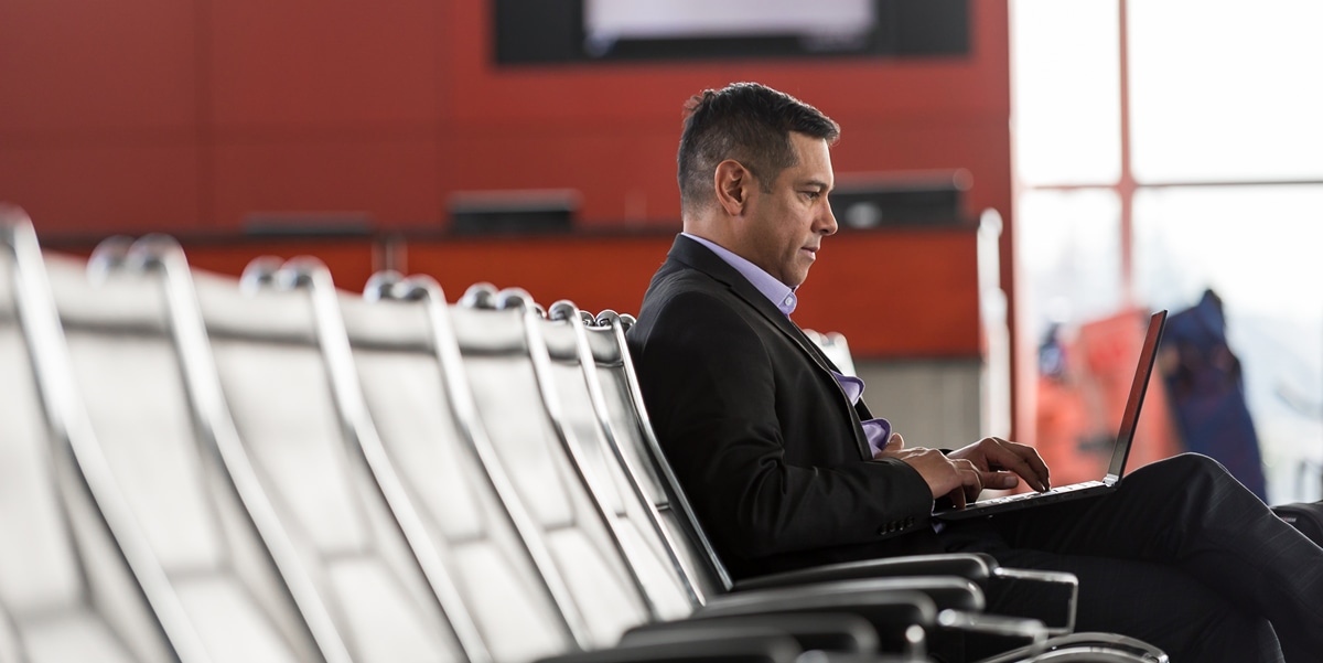 man sitting at airport working on laptop