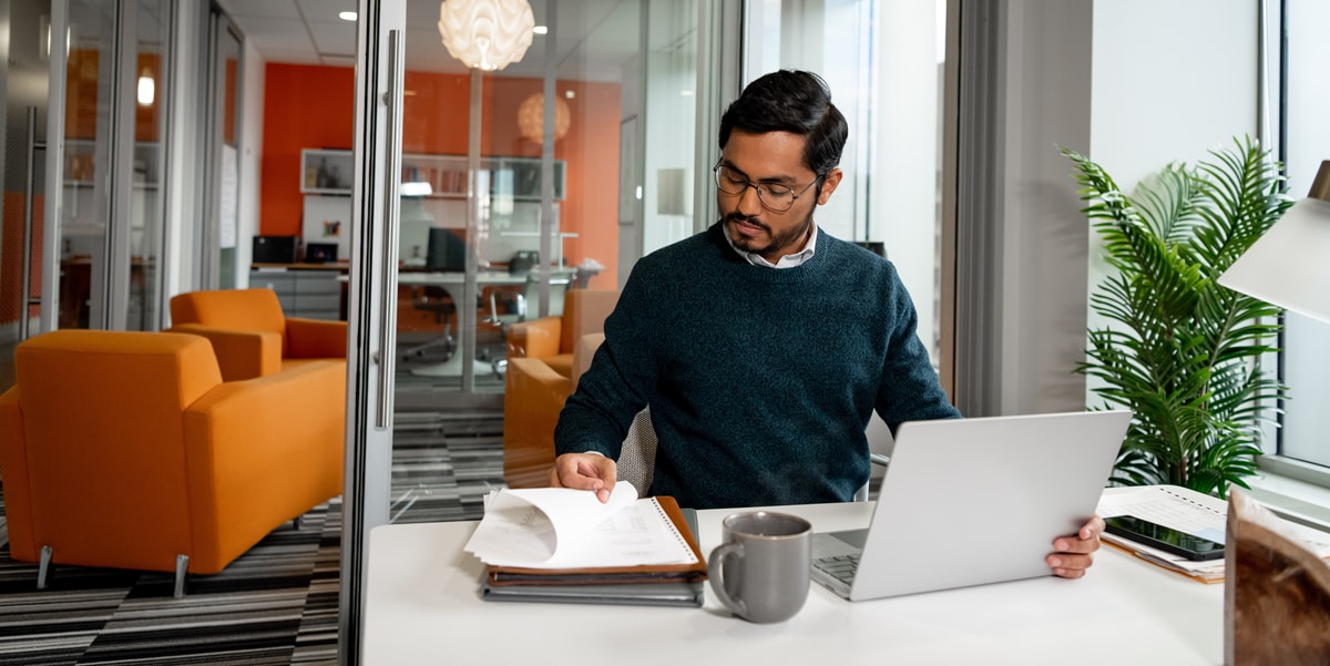 man sitting at desk with documents and laptop