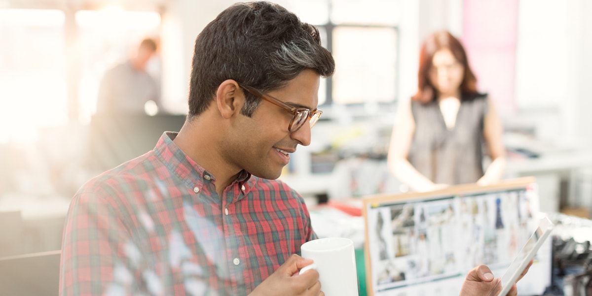 Man holding coffee cup and phone in office space