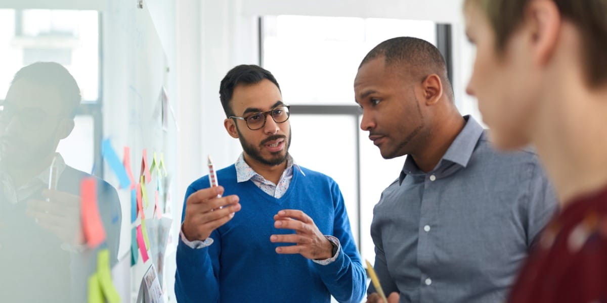 three coworker collaborating on a whiteboard together