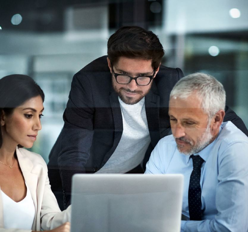 three coworkers looking at a laptop screen together