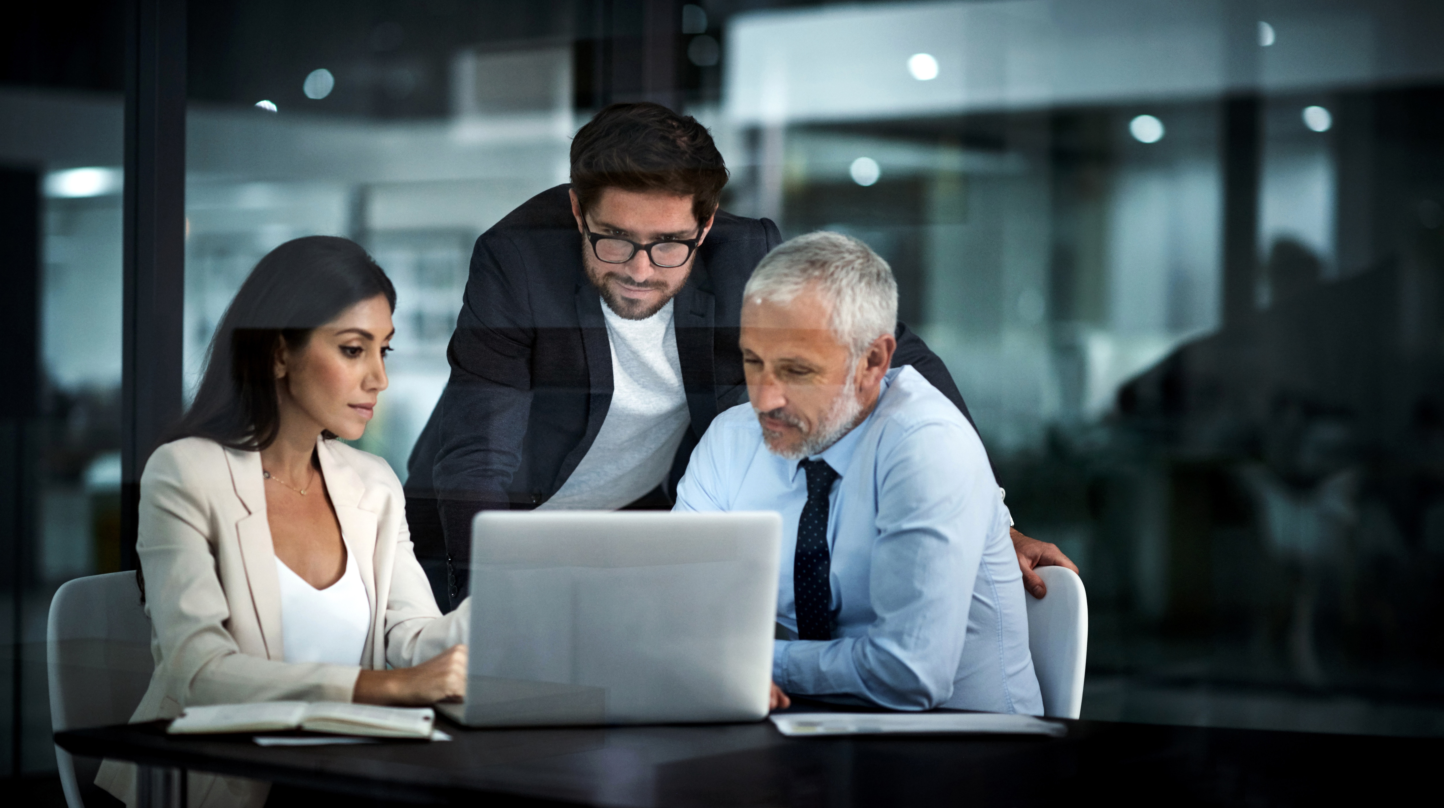 three coworkers looking at a laptop screen toegther