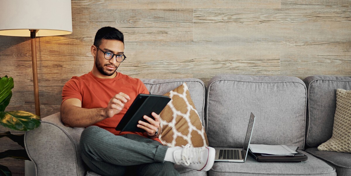 man sitting on couch, using tablet