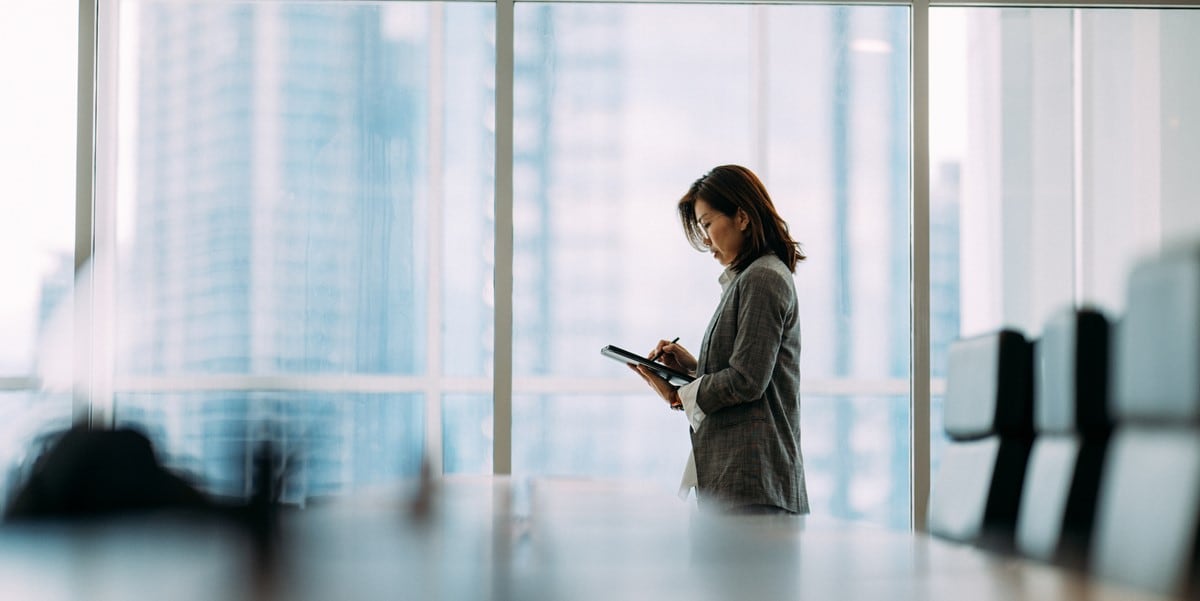 woman standing in conference room looking down at phone