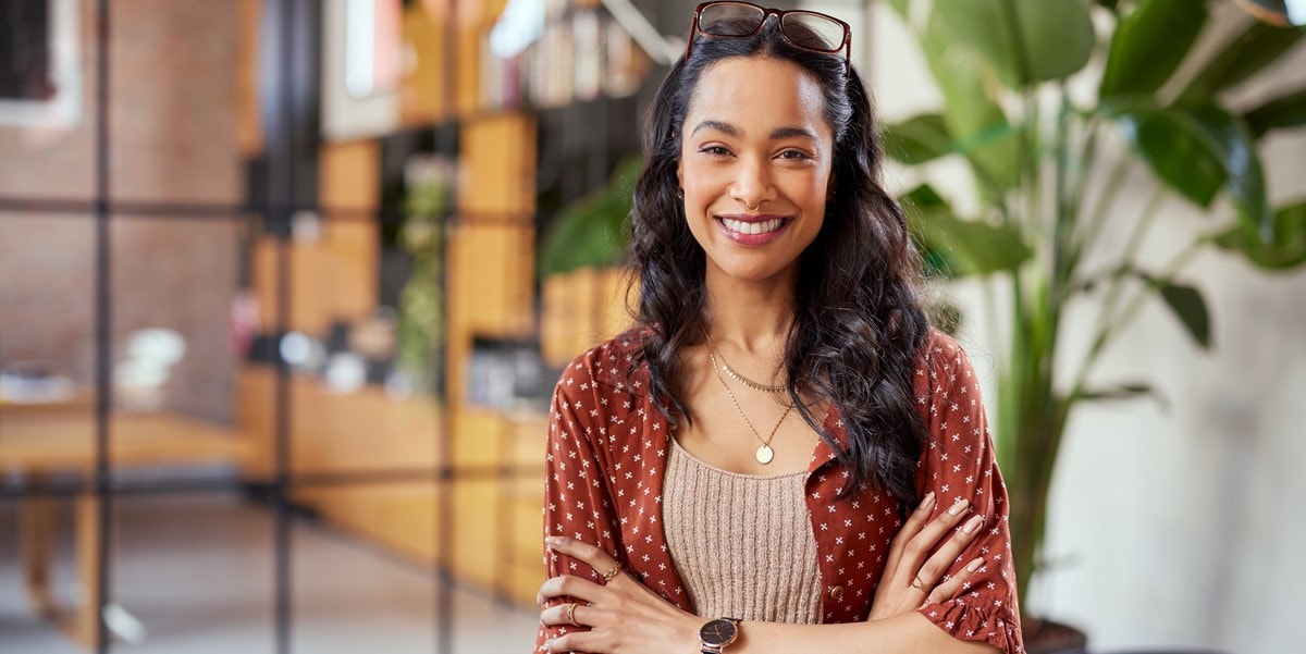 professional woman smiling with arms crossed, in the office