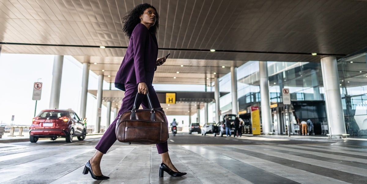 traveler walking into airport holding luggage bag