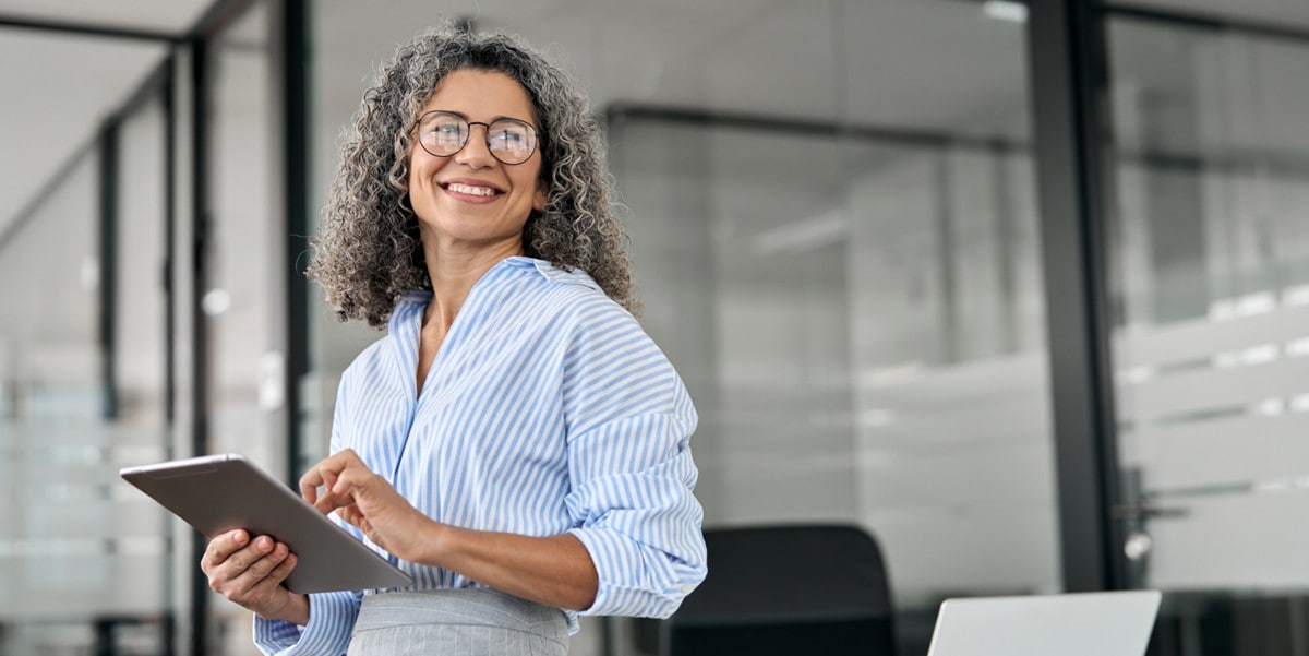 professional woman smiling in the office holding a tablet