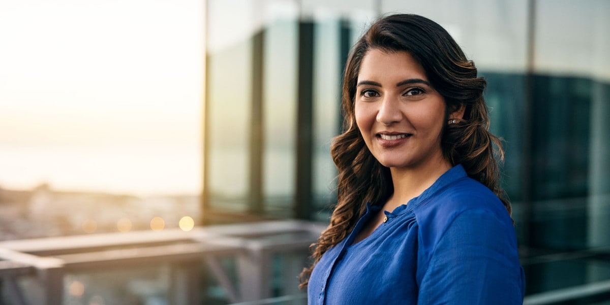 professional woman standing outside office building smiling