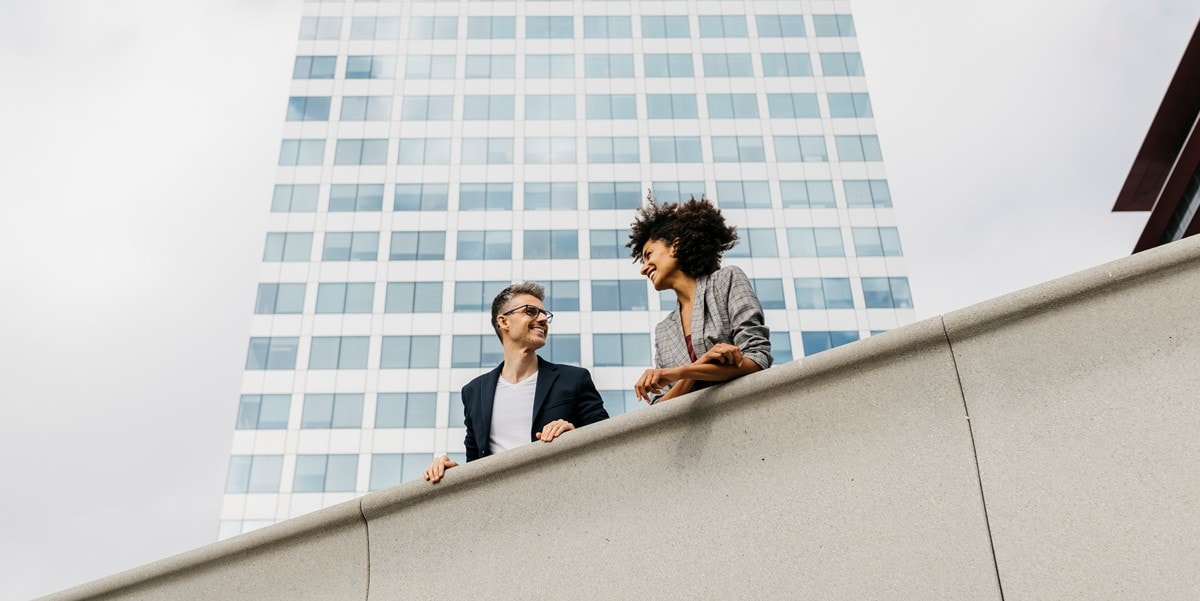 two professional standing outside in front of office building