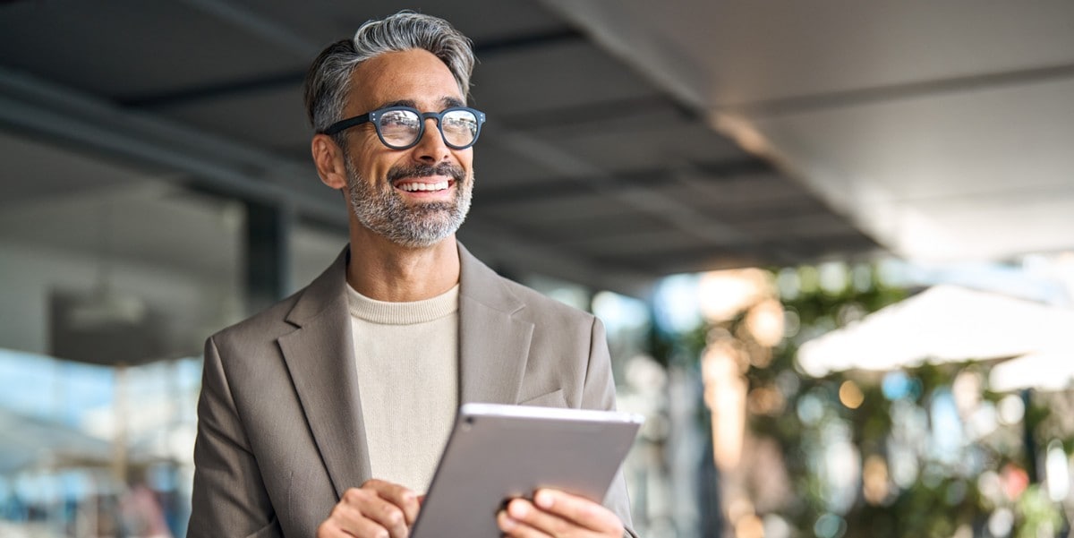 professional man smiling, in the office, holding tablet