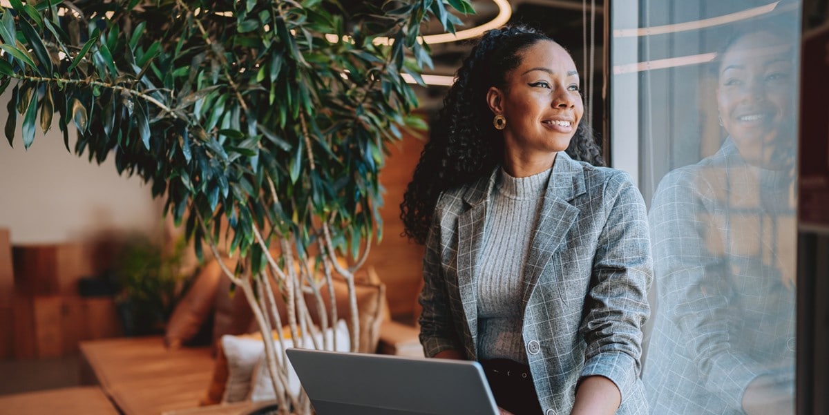 professional woman sitting next to a window working with laptop