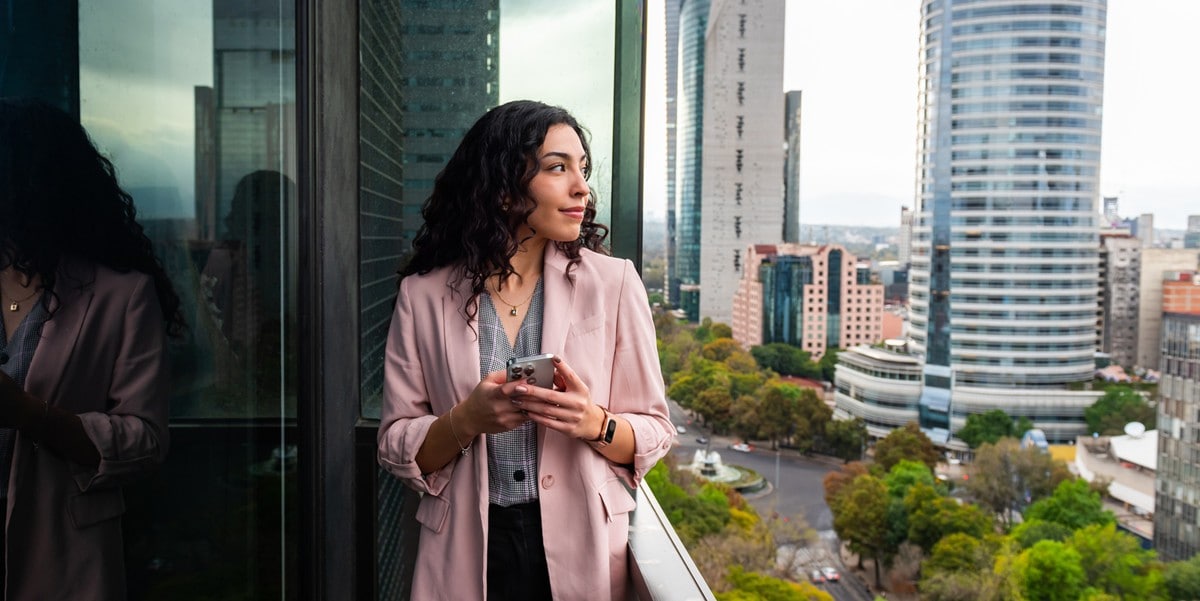professional woman standing on balcony of building, skyscrapes in the background