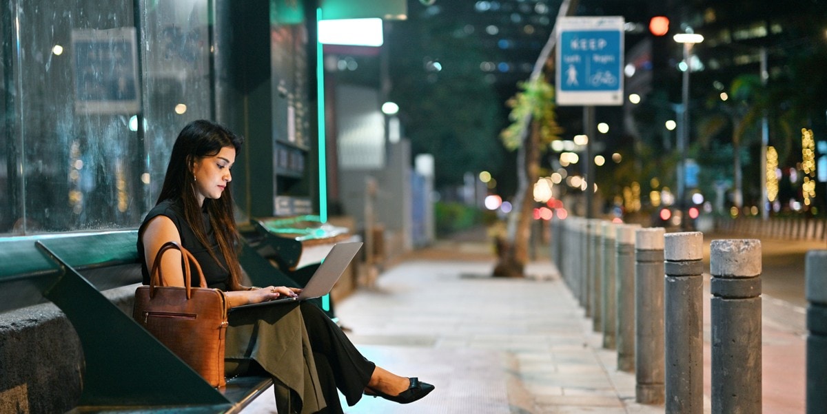 business traveler sitting on bench, using laptop