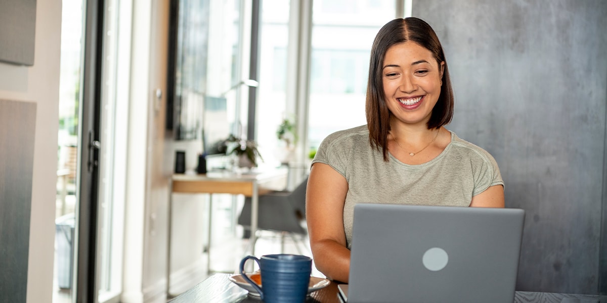 Woman doing her accounts payable from home with a cup of coffee