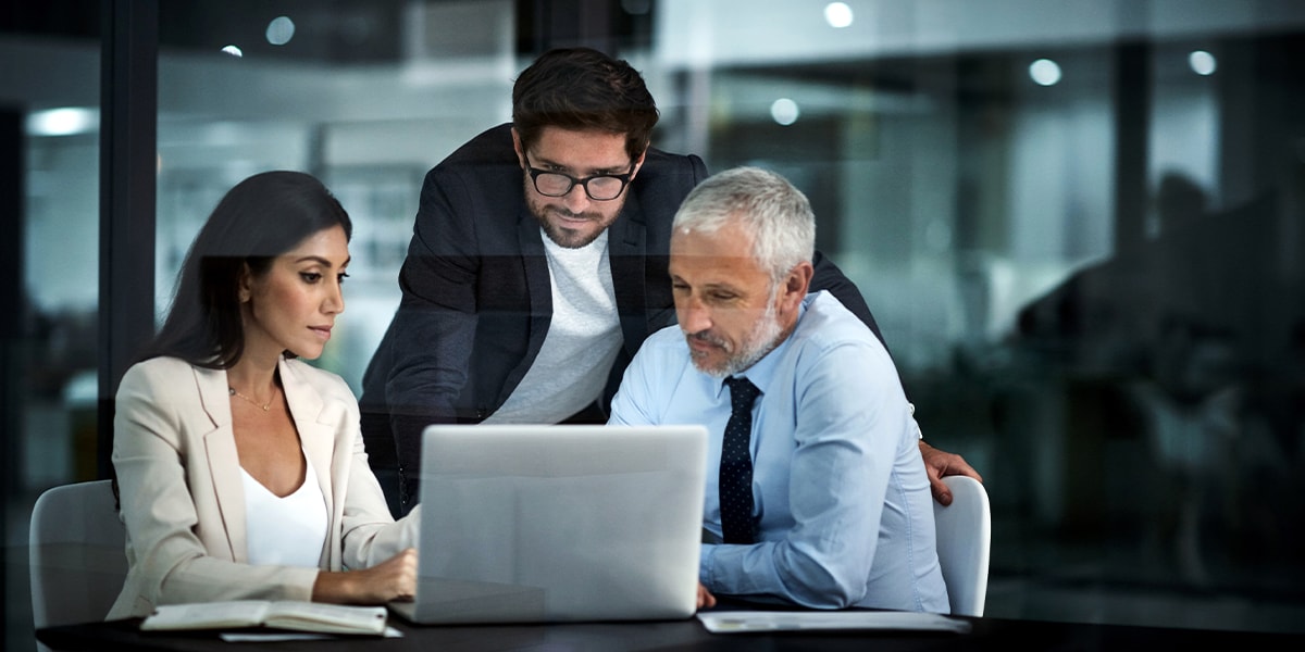 three coworkers looking at a laptop screen together