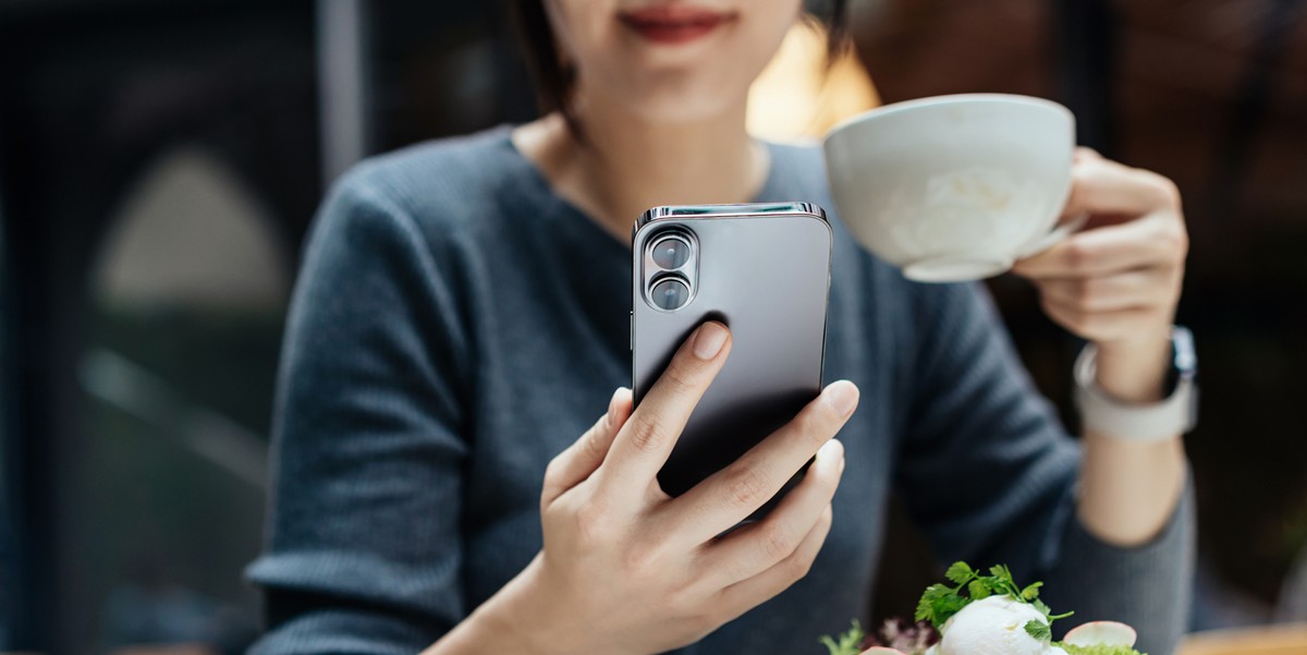 woman holding coffee cup and cell phone