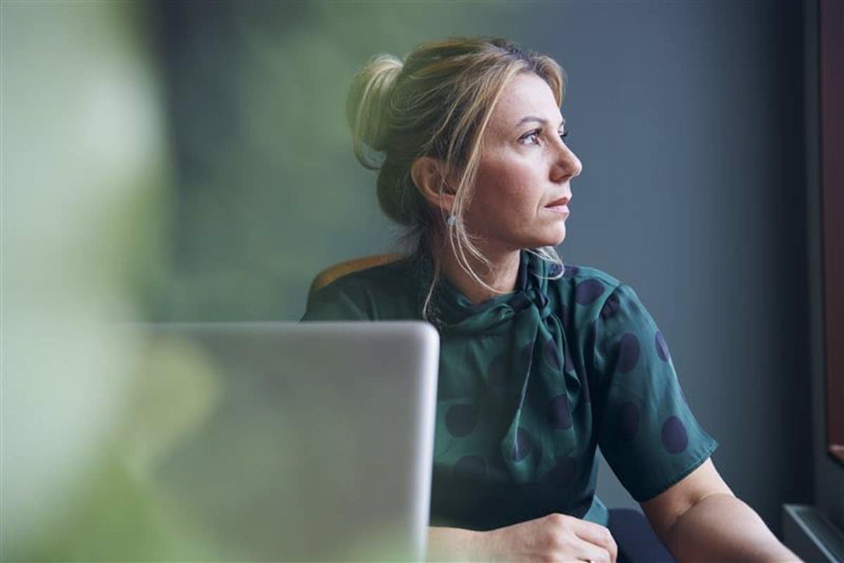 Woman at laptop looking out of window