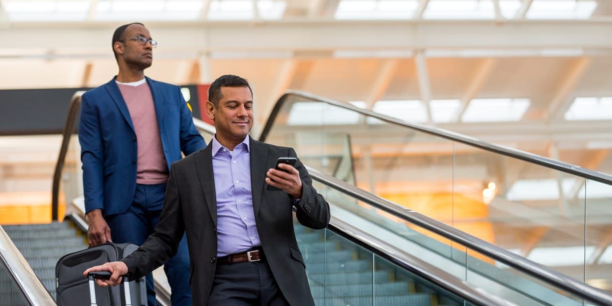 man with luggage on phone airport escalator
