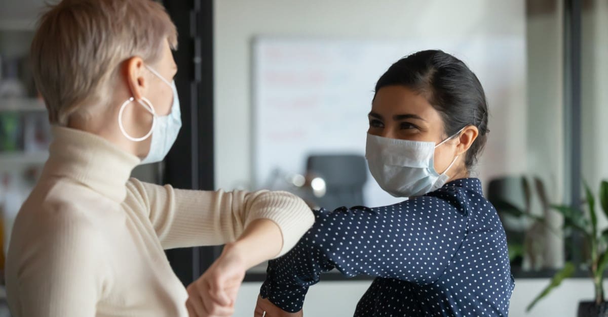 two masked coworkers giving each other an elbow bump