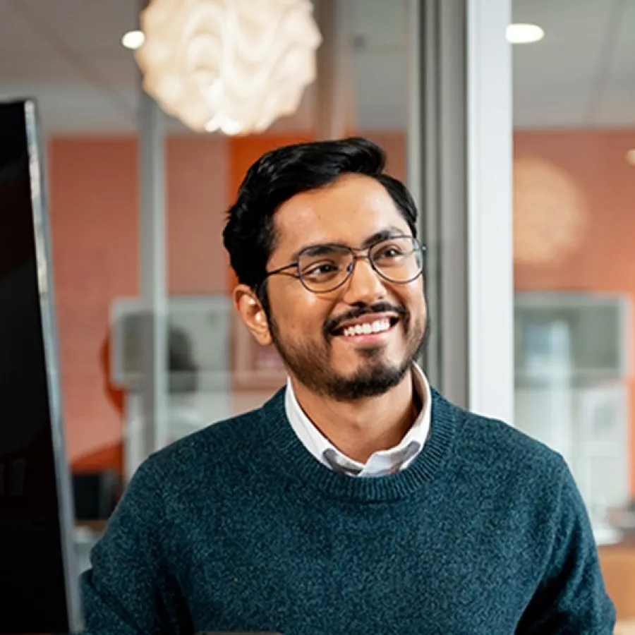 professional man smiling, seated at desk in an office